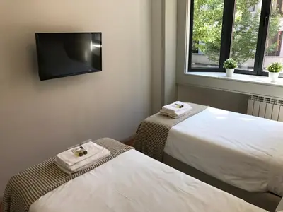 a room with two beds and a flat screen tv at Lux Bolhão - ALL INCLUDED in Porto