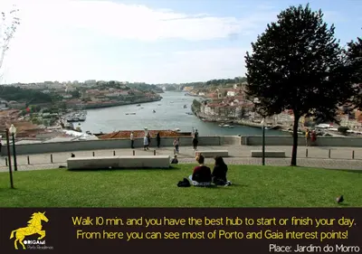 a group of people sitting on the grass looking at a river at Origami Porto Residência & Hostel in Vila Nova de Gaia