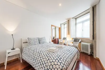 a white bedroom with a bed and a window at GuestReady - Ao Coliseu in Porto