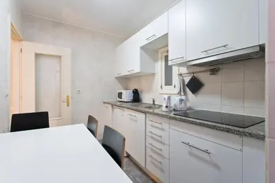 a kitchen with white cabinets and a table and chairs at Home @ Porto Clérigos Apartment in Porto