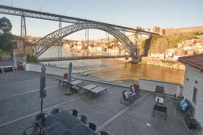 a bridge over a river with tables and chairs at Bridge It - Suites & Views in Vila Nova de Gaia