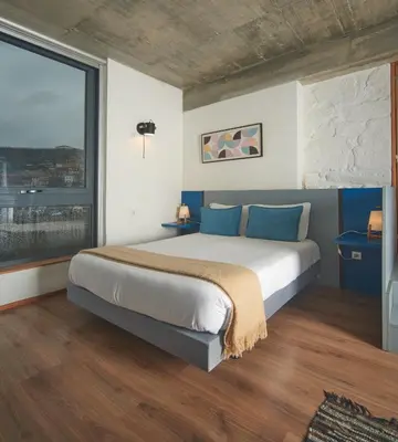a bedroom with a large bed and a large window at Bridge It - Suites & Views in Vila Nova de Gaia