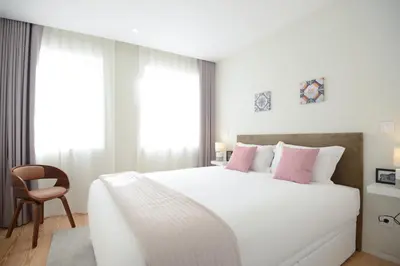 a bedroom with a large white bed with pink pillows at Blue House Porto Apartments - Parking in Porto