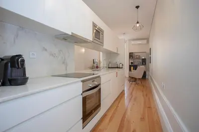 a kitchen with white cabinets and a wooden floor at Liiiving In Porto | Bolhão Market Apartments in Porto