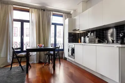 a kitchen with white cabinets and a table with chairs at Sao Bento Studio in Porto