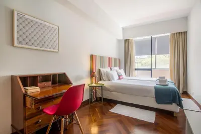 a bedroom with a bed and a desk and a red chair at Cozy Stay - Cedofeita 436 in Porto