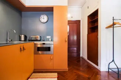 an orange kitchen with a clock on the wall at Cozy Stay - Cedofeita 436 in Porto