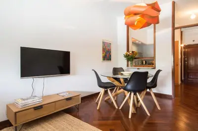 a living room with a table and chairs and a flat screen tv at Cozy Stay - Cedofeita 436 in Porto