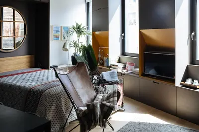 a bedroom with a bed and a chair and a tv at HOMEinTOWN Camões - Modern and Quiet Central Studio - AC & Fast WiFi Near Trindade Metro Station in Porto