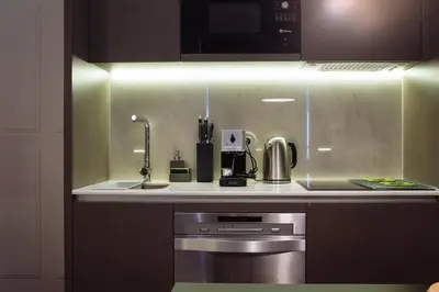 a kitchen with a sink and a stove and a microwave at HOMEinTOWN Camões - Modern and Quiet Central Studio - AC & Fast WiFi Near Trindade Metro Station in Porto