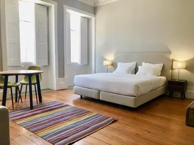 a bedroom with a white bed and a table and a table at Porto Republica Downtown in Porto