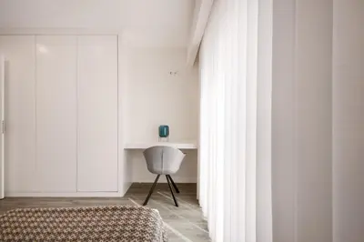 a bedroom with white walls and a bed and a chair at Ribeira Apartments Santa Catarina in Porto