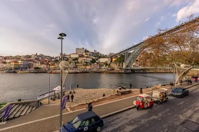 a river with cars parked next to a bridge at YOUROPO - Ribeira Gaia in Vila Nova de Gaia