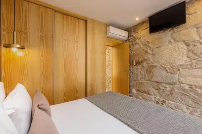a bedroom with a bed and a tv on a stone wall at YOUROPO - Ribeira Gaia in Vila Nova de Gaia
