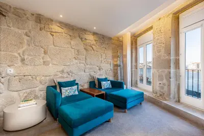 a room with two blue chairs and a stone wall at YOUROPO - Ribeira Gaia in Vila Nova de Gaia