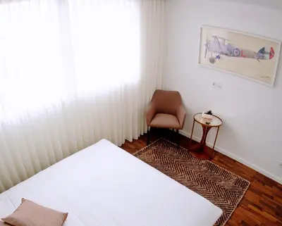 a bedroom with a bed and a chair and a window at Unique Penthouse Porto near Livaria Lello - 40m2 Terrace and Free Parking in Porto