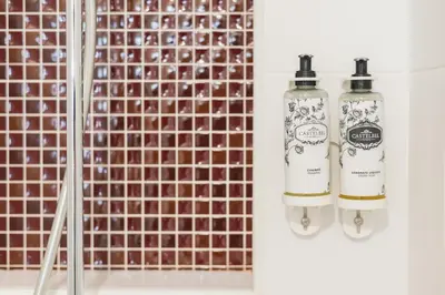 a bathroom with two shampoo bottles in front of a tiled wall at Central Luxury apartment w AC Downtown and Metro in Porto