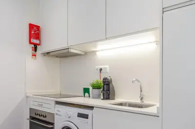 a white kitchen with a sink and a dishwasher at Renovated & Quiet 1-Bedroom in Santa Catarina in Porto