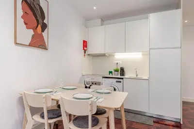 a kitchen with a table and chairs and a kitchen with white cabinets at Renovated & Quiet 1-Bedroom in Santa Catarina in Porto