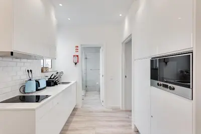 a white kitchen with white counters and a sink at Central Porto 1BR Apartment - Oporto Bridges in Porto