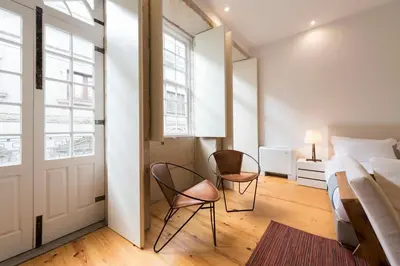 a bedroom with two chairs and a bed and a door at LovelyStay - Rico's Apartment - Almada 2º F in Porto