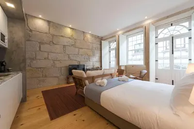 a bedroom with a large white bed and a kitchen at LovelyStay - Rico's Apartment - Almada 2º F in Porto
