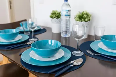 a table with blue bowls and plates and wine glasses at Downtown Porto Bonfim Studio Apt in Porto