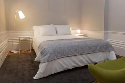 a bedroom with a bed and a green chair at AD Apartment - Solar da Avenida in Porto