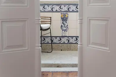an open door with a chair and a tile wall at AD Apartment - Solar da Avenida in Porto