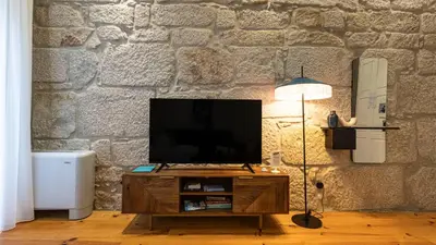 a tv on a wooden stand in a room with a stone wall at LovelyStay - Allderman Apartment - Almada 1º T in Porto