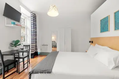 a bedroom with a large white bed and a desk at OX Apartments B Places in Porto
