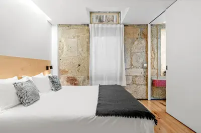 a bedroom with a white bed and a brick wall at OX Apartments B Places in Porto