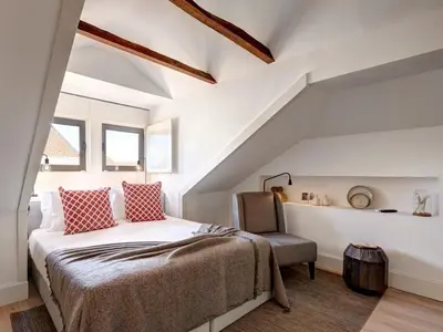 a attic bedroom with a bed and a chair at ApartmentsPorto - Bombarda 451 in Porto