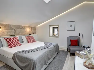 a bedroom with a large bed and a chair at ApartmentsPorto - Bombarda 451 in Porto