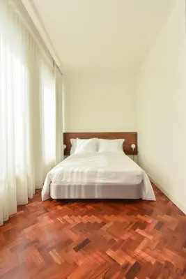 a bedroom with a white bed and a wooden floor at Republica 157 Guest House in Porto