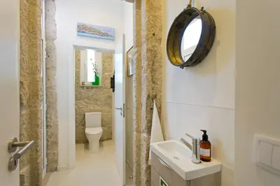 a bathroom with a sink and a toilet and a mirror at Luxurious Pink House and Parking in Porto