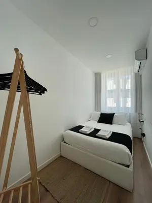 a white bedroom with a bed and a wooden tripod at Casa da Ana - Porto Velho Apt in Porto
