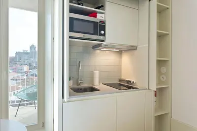 a white kitchen with a sink and a window at Vitoria Studio Residence - Downtown in Porto