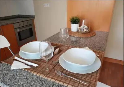 a table with two white plates and wine glasses at Cosy Santa Catarina Flat in Porto