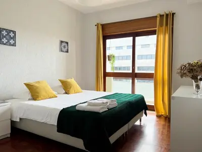 a bedroom with a bed with yellow and green sheets and a window at Boavista YourHome in Porto