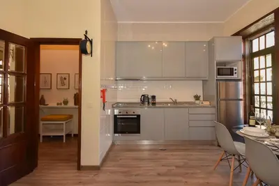 a kitchen with white cabinets and a table and chairs at Azulejos Duplex Apartment - Porto Downtown in Porto