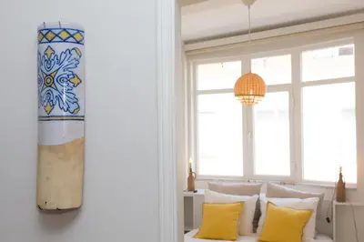 a room with a bed with yellow pillows and a chandelier at Porto Haven - Vintage Apartment in Downtown in Porto