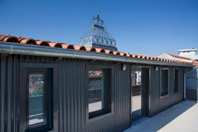 a building with windows with a tower in the background at Oporto Avenue Attic - Solar da Avenida in Porto