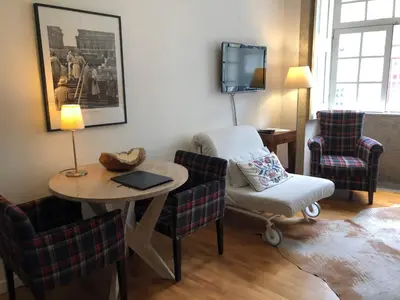 a living room with a table and chairs and a tv at PortoSense Ribeira in Porto