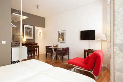 a bedroom with a red chair and a dining room at PortoSense Ribeira in Porto
