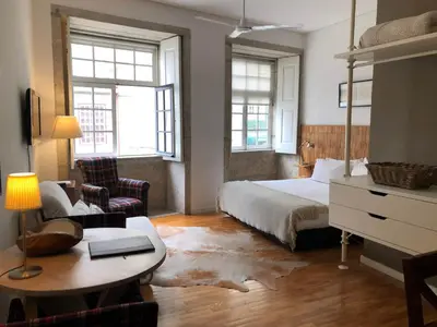 a bedroom with a bed and a desk and a table at PortoSense Ribeira in Porto