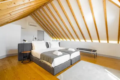 a bedroom with a bed in a loft with wooden ceilings at Thomaz Palace in Porto