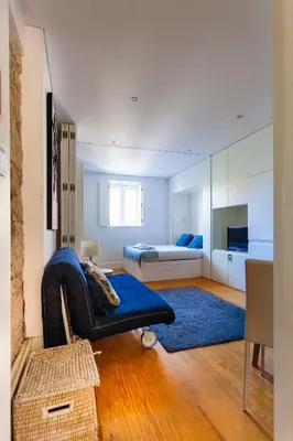 a living room with a blue couch and a bedroom at Citybreak-Apartments Poveiros in Porto