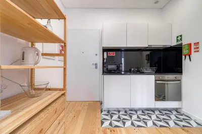 a kitchen with white cabinets and a black and white checkered floor at Nomad's Netto & Subway in Porto