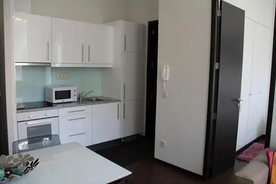 a kitchen with white cabinets and a black refrigerator at 12 Short Term in Porto